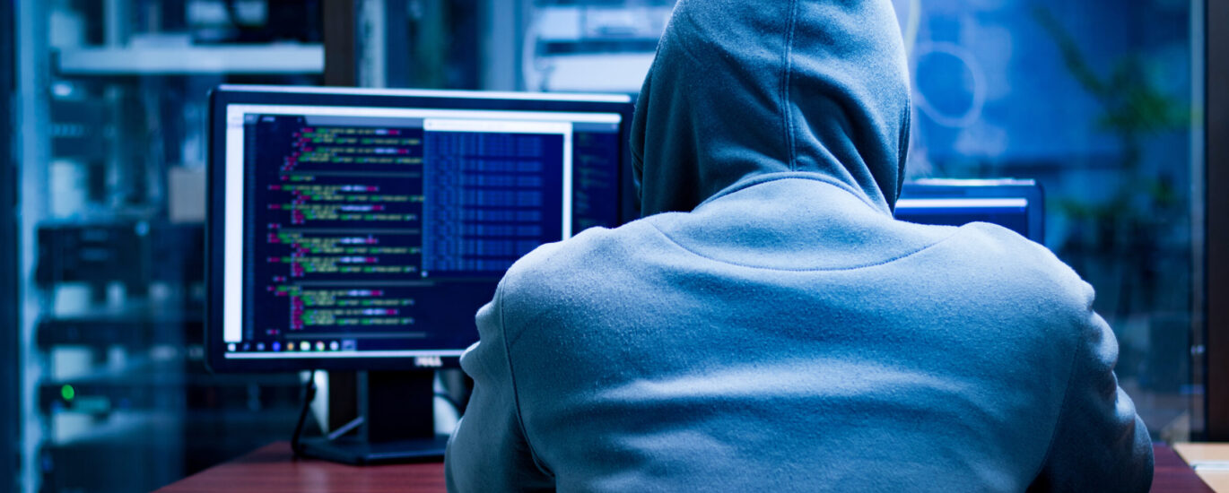 a person in a hoodie looking at a computer screen